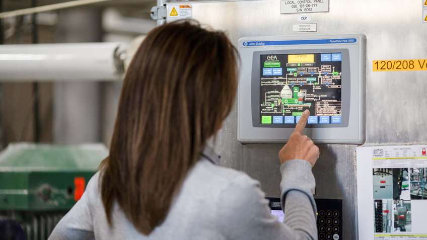 Operator using an Allen-Bradley PanelView Plus touchscreen HMI to monitor a process at a local control panel