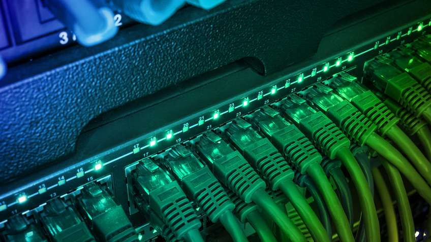 Ethernet switch ports with green patch cables and active link indicators in a network cabinet