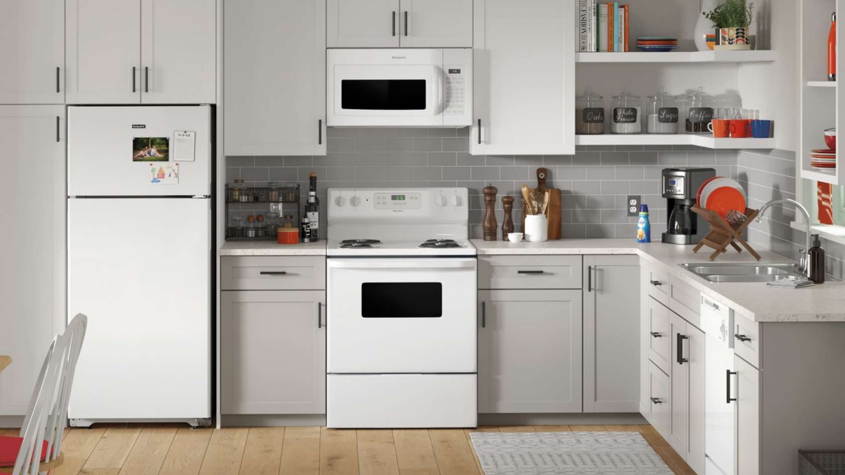 Hotpoint white refrigerator, electric range, and over-range microwave in a bright everyday kitchen