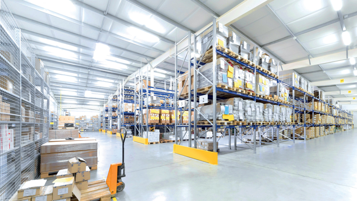 Wide aisle of pallet racking stocked with cartons in a warehouse with overhead lighting
