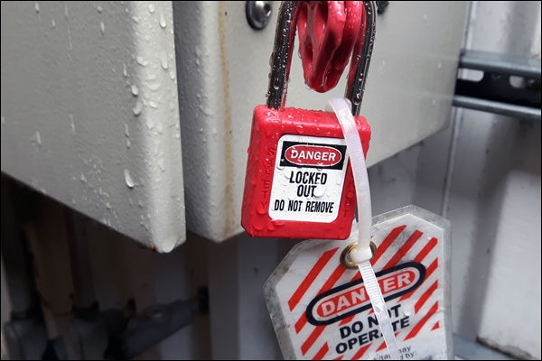 Lockout tagout padlock and warning tag applied to a disconnect during energy isolation