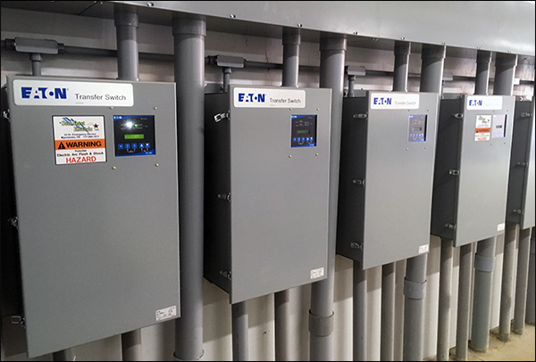 Row of wall-mounted Eaton automatic transfer switches with conduit runs and digital controllers